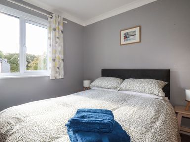 A bedroom with a bed with patterned bedding and folded blue towels on it at Coombe Cottage in Falmouth