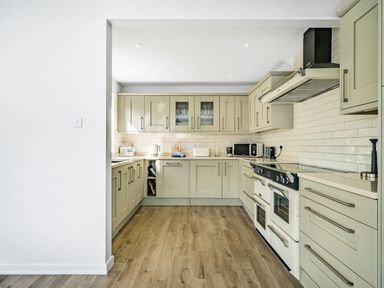 A kitchen with cabinets countertops a stove microwave and wooden floor at Fairwinds in Portreath