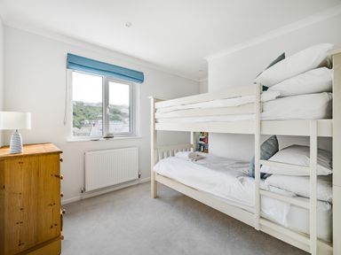 A bedroom with a bunk bed dresser and a window with a blue blind at Fairwinds in Portreath