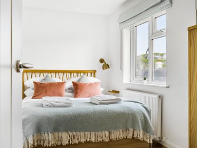 A bedroom with a bed with pillows and folded towels near a window at Fairwinds in Portreath
