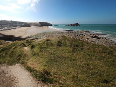A coastal landscape with a sandy beach rocky shoreline and grassy foreground at Fairwinds in Portreath