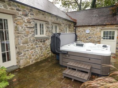 An outdoor patio area with a hot tub and stone walls at St Dogwells Barn near Wolfscastle