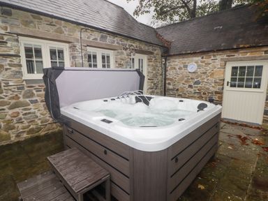 An outdoor hot tub with water jets in a stone courtyard at St Dogwells Barn near Wolfscastle