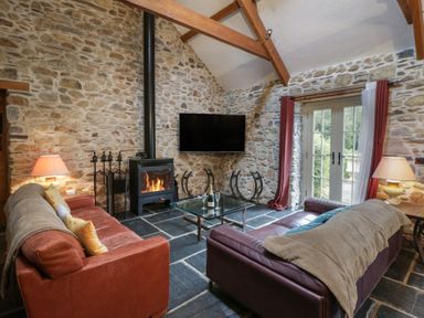 A living room with a sofa, coffee table, and fireplace at St Dogwells Barn near Wolfscastle