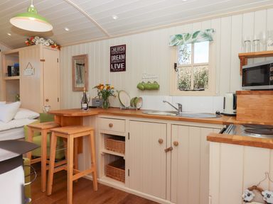 A kitchen with wooden countertops stools sink microwave and small window at Shepherds Joy in Kennerleigh near Cheriton Fitzpaine