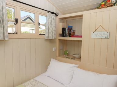 A bedroom corner with a bed white pillows built in shelves books and a sign on the wall at Shepherds Joy in Kennerleigh near Cheriton Fitzpaine