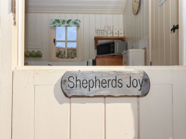A kitchen with a microwave bread bin and mugs hanging near a window at Shepherds Joy Kennerleigh near Cheriton Fitzpaine