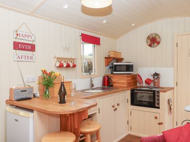 A kitchen with wooden countertops stools a microwave oven and a stove at Shepherds Bliss Kennerleigh near Cheriton Fitzpaine