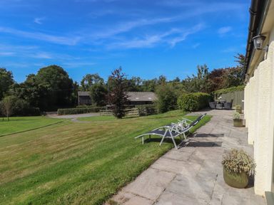 A garden with lawn chairs and potted plants on a stone patio at Binneford Barn in Kennerleigh near Cheriton Fitzpaine