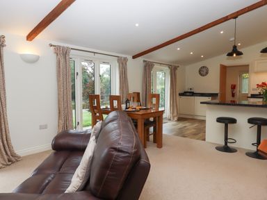 A living room with a brown leather sofa wooden dining table and kitchen area at Binneford Barn Kennerleigh near Cheriton Fitzpaine