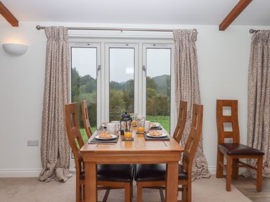 A dining room with a wooden table and six chairs set with plates croissants and glasses of orange juice at Binneford Barn Kennerleigh near Cheriton Fitzpaine