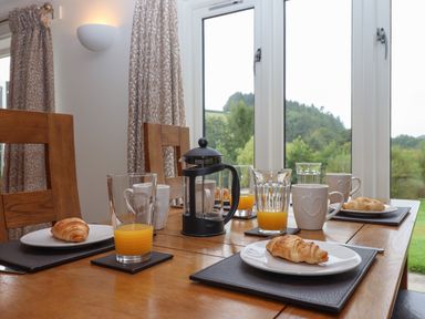 A dining table with plates of croissants glasses of orange juice and a coffee press at Binneford Barn Kennerleigh near Cheriton Fitzpaine