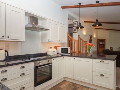 A kitchen with white cabinets black countertops oven microwave kettle and flowers on counter at Binneford Barn Kennerleigh near Cheriton Fitzpaine
