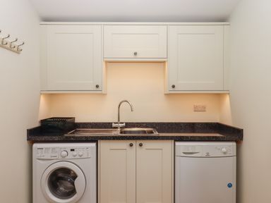 A utility room with washing machine dishwasher sink and cabinets at Binneford Barn Kennerleigh near Cheriton Fitzpaine