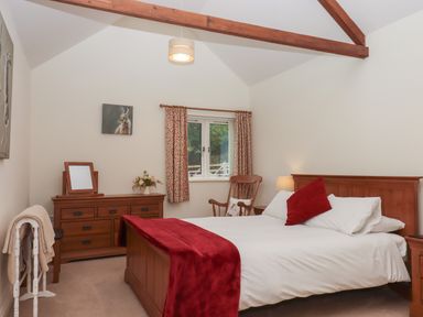 A bedroom with a wooden bed with white bedding and red throw at Binneford Barn Kennerleigh near Cheriton Fitzpaine