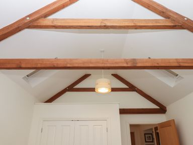 A ceiling with exposed wooden beams a hanging light and two skylights above white doors in Binneford Barn Kennerleigh near Cheriton Fitzpaine