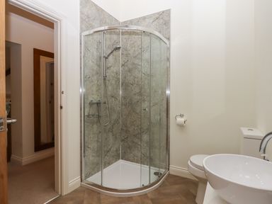 A bathroom with a glass shower enclosure a toilet and a round sink at Binneford Barn Kennerleigh near Cheriton Fitzpaine