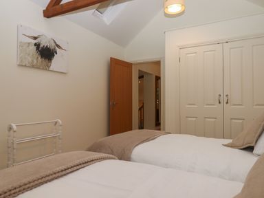 A bedroom with two single beds a wooden door and white closet doors at Binneford Barn Kennerleigh near Cheriton Fitzpaine