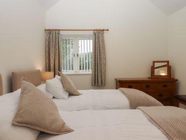 A bedroom with two single beds and a wooden dresser with a mirror at Binneford Barn in Kennerleigh near Cheriton Fitzpaine