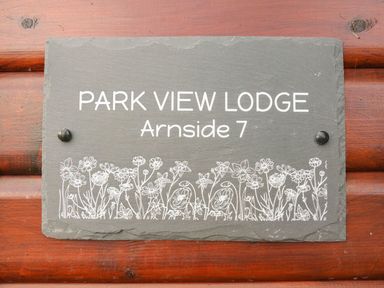A sign on a wooden wall that reads Park View Lodge Arnside 7 with a floral design at the bottom Park View Lodge Arnside 7 South Lakeland Leisure Village near Carnforth