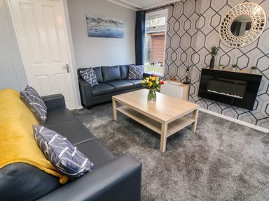 A living room with two sofas a wooden coffee table with flowers and a wall-mounted fireplace at Park View Lodge Arnside 7 South Lakeland Leisure Village near Carnforth