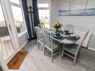 A dining room with a table set for six near a door leading to a patio at Park View Lodge Arnside 7 South Lakeland Leisure Village near Carnforth