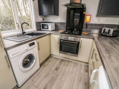 A kitchen with a washing machine microwave oven stove toaster and sink at Park View Lodge Arnside 7 South Lakeland Leisure Village near Carnforth