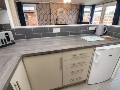 A kitchen counter with a toaster a kettle a small fridge and drawers at Park View Lodge Arnside 7 South Lakeland Leisure Village near Carnforth