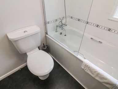 A bathroom with a toilet and a bathtub with a shower attachment and a towel on the side at Park View Lodge Arnside 7 South Lakeland Leisure Village near Carnforth