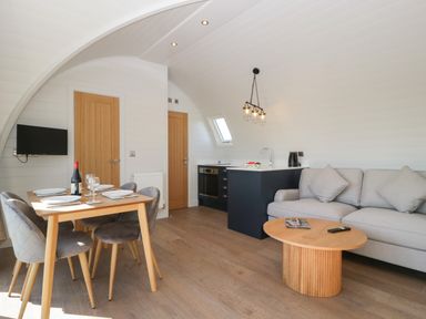 A living room with dining table chairs sofa coffee table and kitchen area at Leadon View Oak in Upleadon near Newent