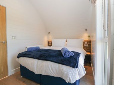 A bedroom with a double bed white bedding and blue blankets at Leadon View Oak in Upleadon near Newent