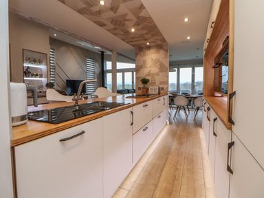 A kitchen with wooden countertops white cabinets a dining table and chairs and a living area at The Lodge @ Racecourse House Babell near Holywell
