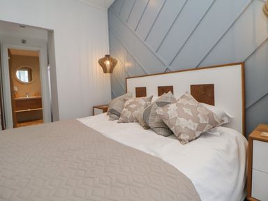 A bedroom with a bed with patterned pillows and a beige blanket at The Lodge @ Racecourse House in Babell near Holywell