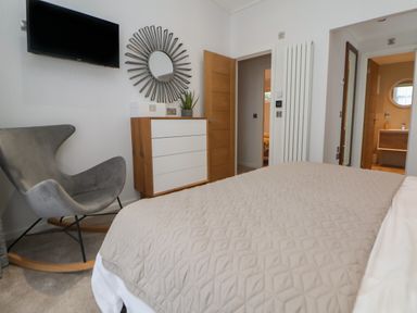A bedroom with a bed gray rocking chair dresser and wall mirror at The Lodge @ Racecourse House in Babell near Holywell