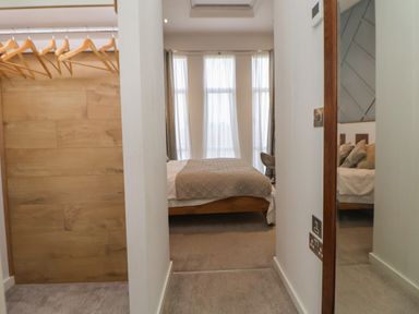A bedroom with a bed covered by a textured blanket and large windows with curtains at The Lodge @ Racecourse House Babell near Holywell
