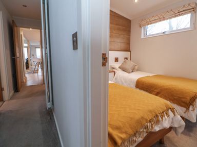 A hallway leading to a room with two single beds covered with yellow blankets at The Lodge @ Racecourse House Babell near Holywell