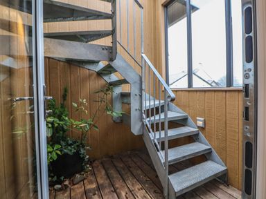 A metal spiral staircase on a wooden deck with potted plants and large window at The Lodge @ Racecourse House Babell near Holywell