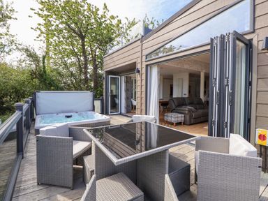 An outdoor patio with a hot tub and dining table at The Lodge @ Racecourse House in Babell near Holywell