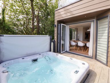 An outdoor area with a hot tub and an open entrance to a dining area at The Lodge @ Racecourse House, Babell near Holywell