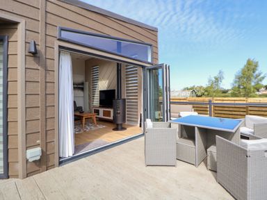 An outdoor terrace with seating and open sliding doors at The Lodge @ Racecourse House Babell near Holywell