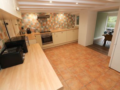 A kitchen with tiled floor and backsplash wooden countertops oven toaster and microwave at Rushfield in St Dogmaels North Pembrokeshire