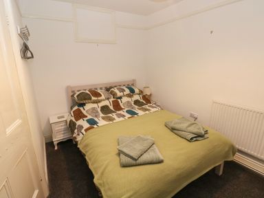 A bedroom with a bed a bedside table with a lamp and folded towels on the bed at Rushfield in St Dogmaels North Pembrokeshire