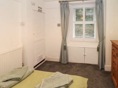 A bedroom with a bed folded towels on it a window with curtains and a wooden chest of drawers at Rushfield in St Dogmaels North Pembrokeshire