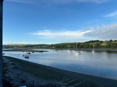 A river with several boats anchored near the shore and green hills in the background at Rushfield in St Dogmaels North Pembrokeshire