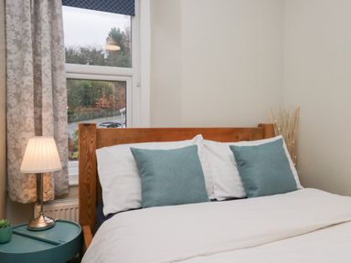 A bedroom with a bed and bedside lamp at The Wonky Nest in Bowness-On-Windermere
