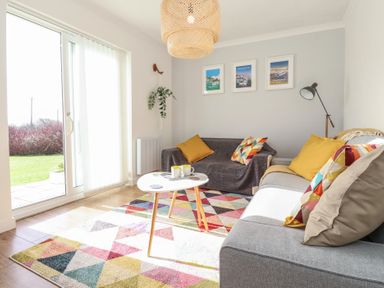A living room with two sofas a small white coffee table and framed pictures on the wall at Beachcomber in Maer near Bude