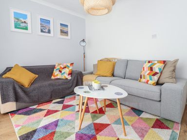 A living room with two sofas and a colorful triangular patterned rug at Beachcomber in Maer near Bude
