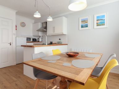 A kitchen and dining area with a wooden table and colorful chairs at Beachcomber Maer near Bude