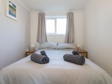 A bedroom with a bed with rolled towels pillows side tables and lamps at Beachcomber in Maer near Bude