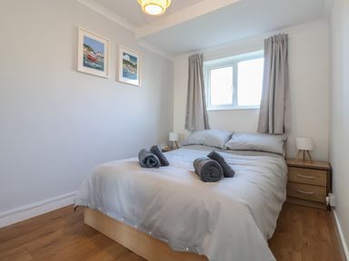 A bedroom with a bed two bedside tables with lamps two framed pictures on the wall at Beachcomber Maer near Bude